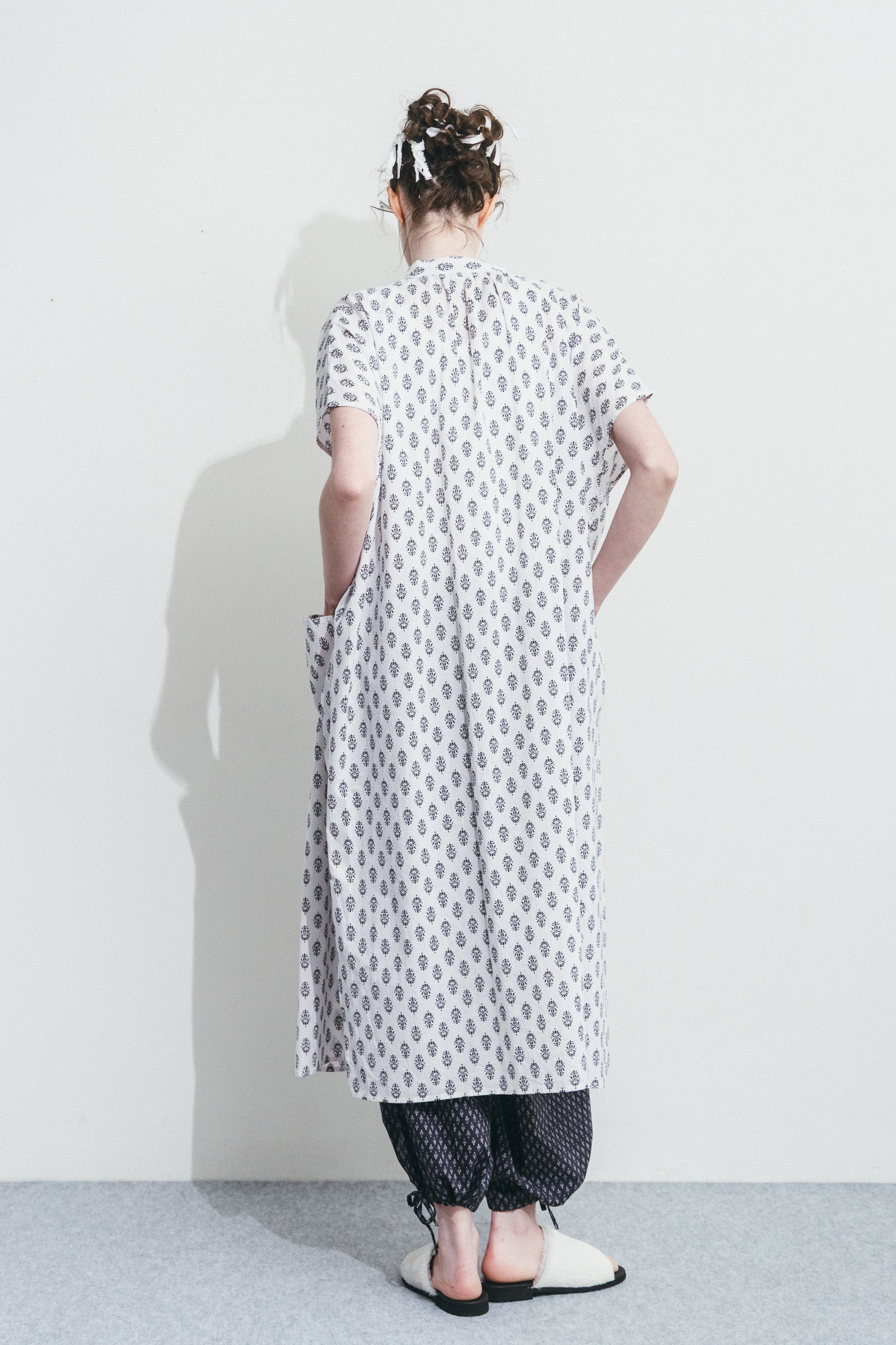 Person wearing a long, patterned dress against a white background